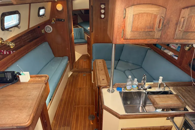 Slide: The Image of Interior of 1994 Pacific Seacraft Crealock 37 sailboat with wooden cabinetry and blue seating. - 1