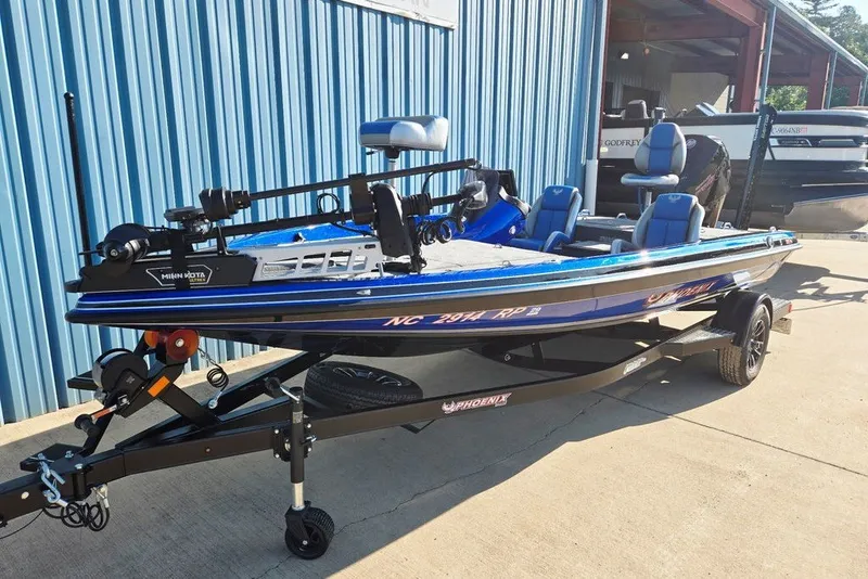 Slide: The Image of 2026 Phoenix 818 Pro fishing boat on trailer, blue exterior, parked by a blue building. - 3