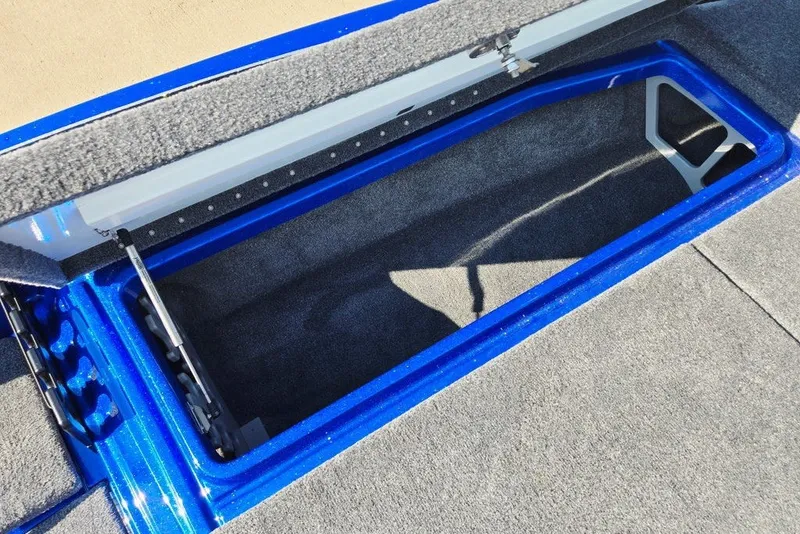 Slide: The Image of Open storage compartment in 2026 Phoenix 818 Pro boat, featuring blue trim and carpeted interior. - 23