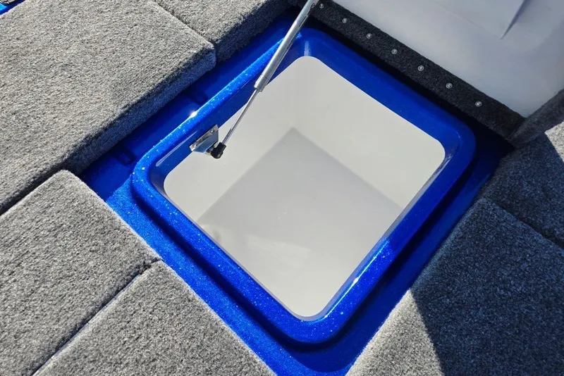 Slide: The Image of Open storage compartment in 2026 Phoenix 818 Pro boat, featuring blue trim and gray carpet. - 60