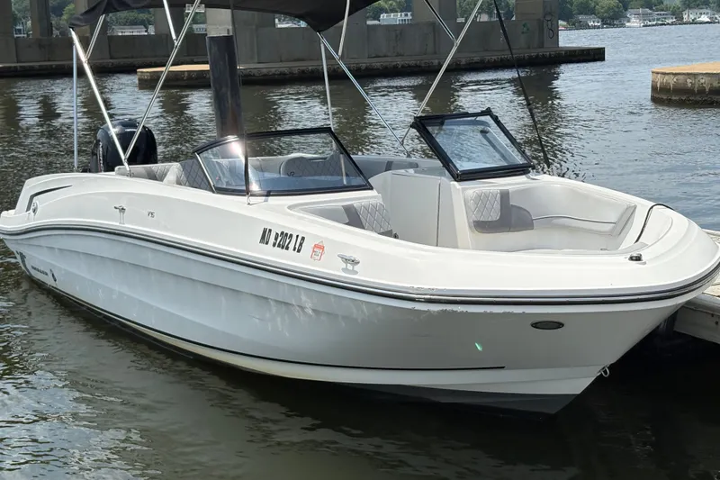 Slide: The Image of 2023 Bayliner VR6 Bowrider OB docked on calm water. - 2