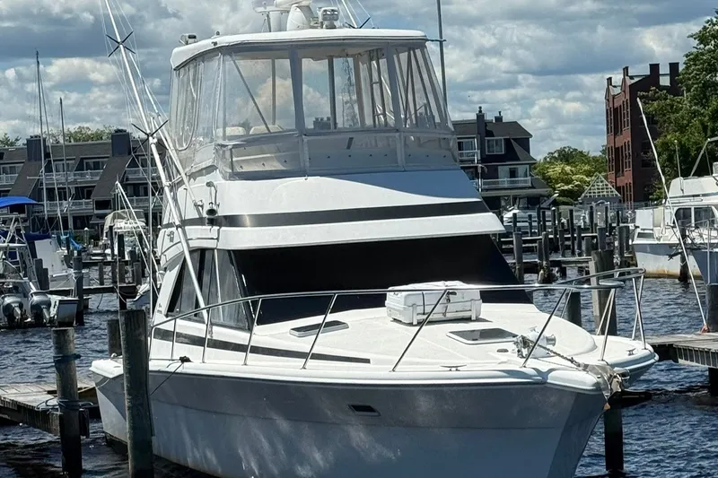 Slide: The Image of 1997 Riviera 34 Convertible yacht docked at a marina under a cloudy sky. - 11