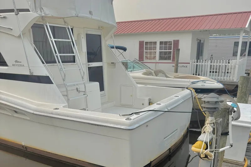 Slide: The Image of 1997 Riviera 34 Convertible yacht docked near a waterfront lodge. - 22