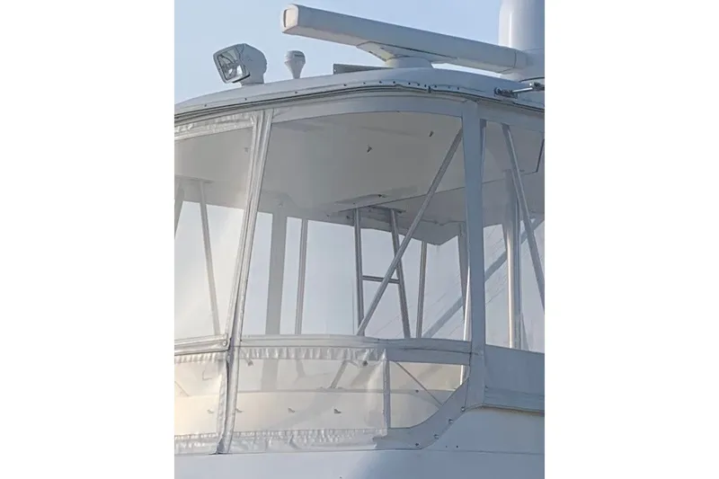 Slide: The Image of 1997 Riviera 34 Convertible boat with enclosed flybridge, featuring clear panels and sturdy framework. - 30