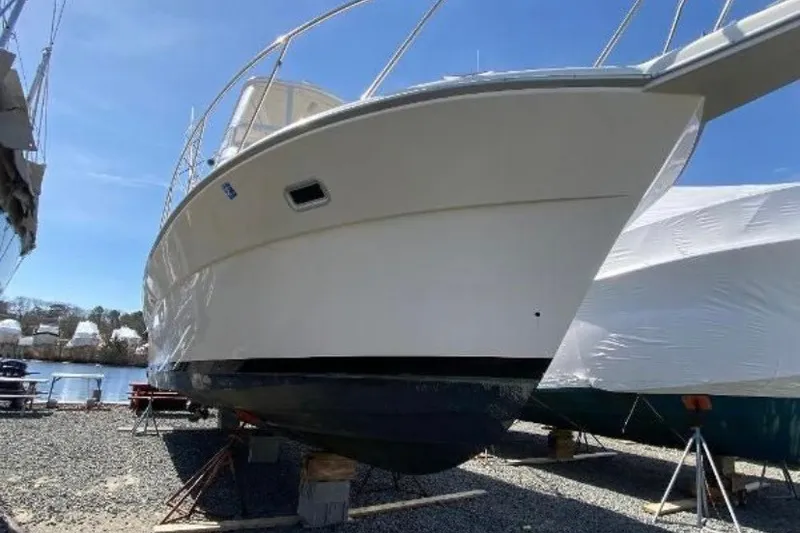 Slide: The Image of 1997 Riviera 34 Convertible boat on dry dock, under clear blue sky. - 7