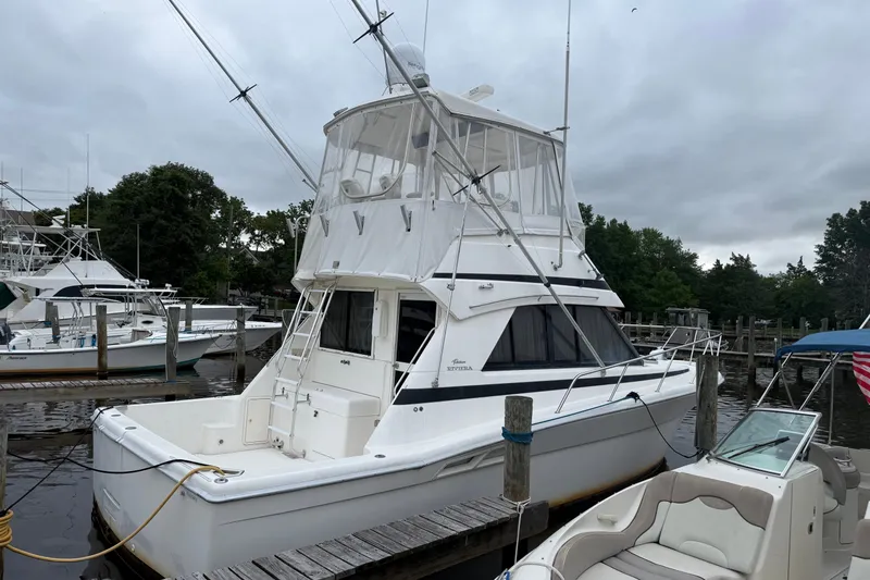 Slide: The Image of 1997 Riviera 34 Convertible yacht docked at marina under cloudy skies. - 1