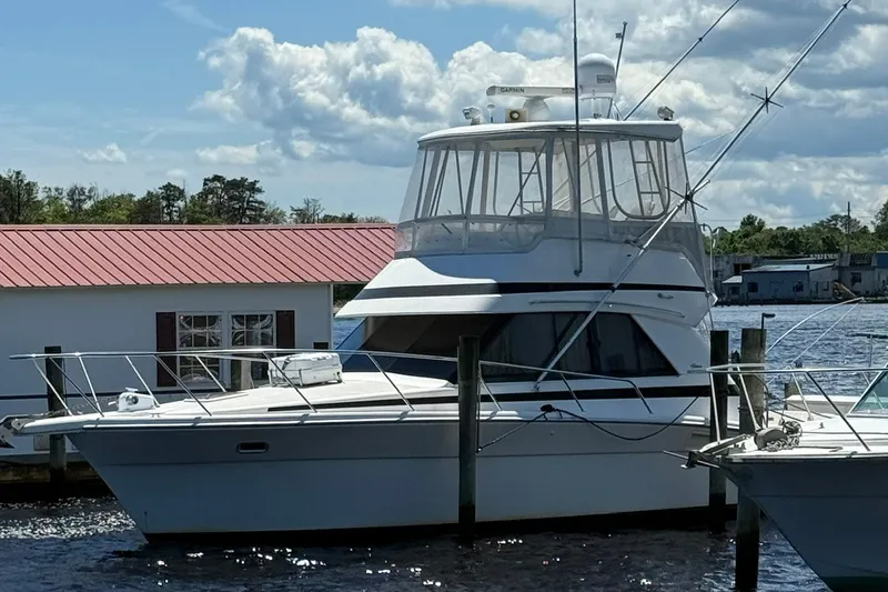 Slide: The Image of 1997 Riviera 34 Convertible yacht docked by a marina under a partly cloudy sky. - 12