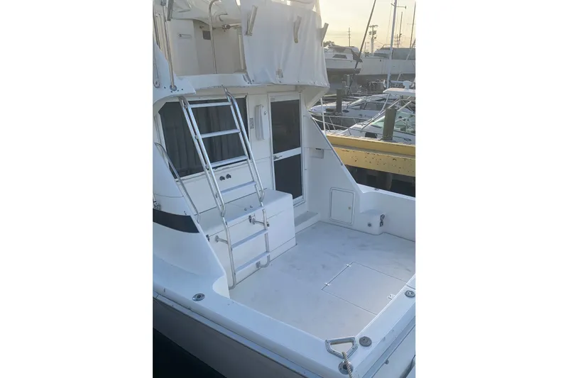 Slide: The Image of 1997 Riviera 34 Convertible yacht with spacious deck and ladder in marina setting. - 29