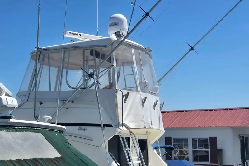 Slide: The Image of 1997 Riviera 34 Convertible boat with enclosed flybridge and antennas, under clear blue sky. - 25