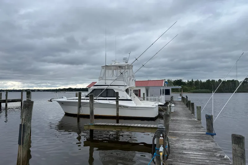 Slide: The Image of 1997 Riviera 34 Convertible yacht docked at a wooden pier under cloudy skies. - 2