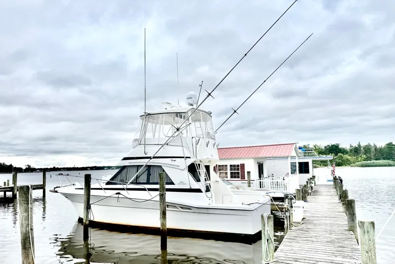 Slide: The Image of 1997 Riviera 34 Convertible yacht docked at a marina under cloudy skies. - 3