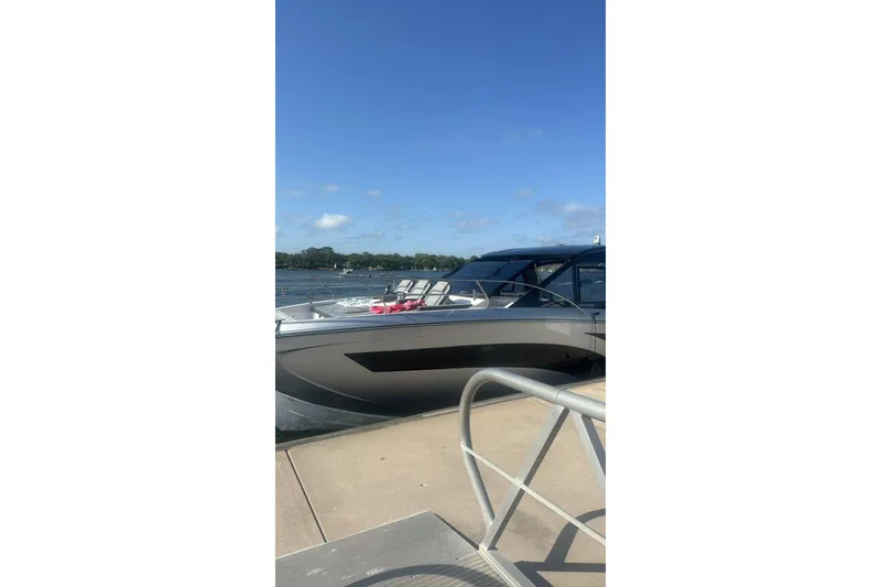 Slide: The Image of Modern Hanover 387 boat docked by a serene lake, clear blue sky, 2025 model. - 5