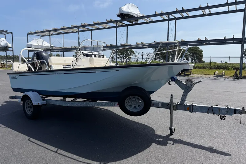 Slide: The Image of 2022 Boston Whaler 170 Montauk boat on trailer, parked outdoors under a clear sky. - 3