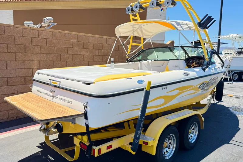 Slide: The Image of 2003 Centurion Cyclone C4 boat with yellow accents on a trailer, parked outdoors. - 5