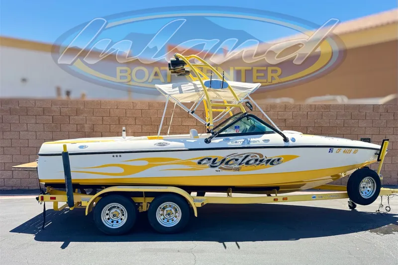 The Image of 2003 Centurion Cyclone C4 boat on trailer, yellow and white design, parked outdoors. - 0