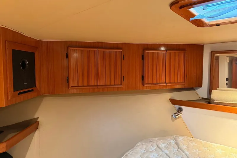 Slide: The Image of Interior of a 1996 Post 50 Convertible yacht with wooden cabinets and cozy bedding. - 26