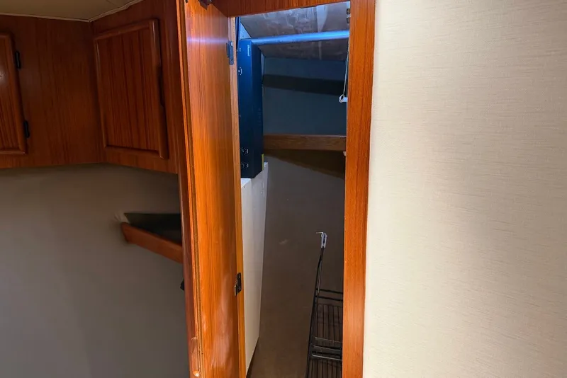Slide: The Image of Interior view of a 1996 Post 50 Convertible yacht, featuring wooden cabinetry and storage space. - 28
