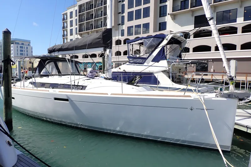 Slide: The Image of 2018 Jeanneau Sun Odyssey 389 sailboat docked at marina, modern buildings in background. - 1
