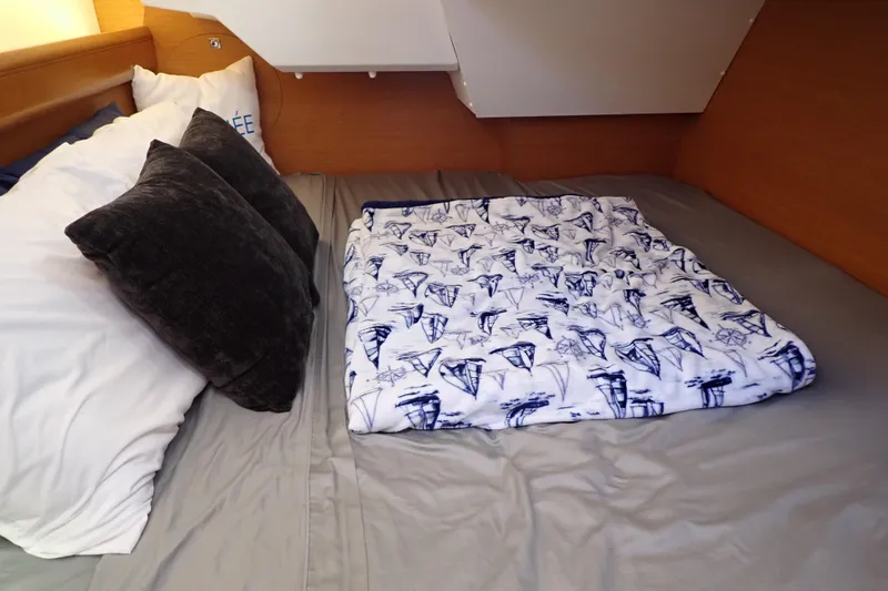 Slide: The Image of Cozy cabin bed in 2018 Jeanneau Sun Odyssey 389 sailboat with nautical-themed blanket. - 62