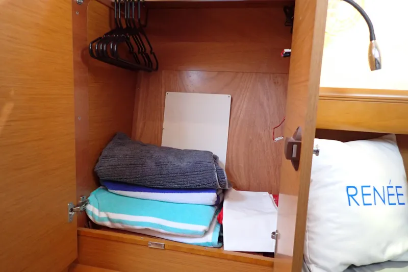 Slide: The Image of Cabinet interior on 2018 Jeanneau Sun Odyssey 389 with folded towels and hangers. - 152