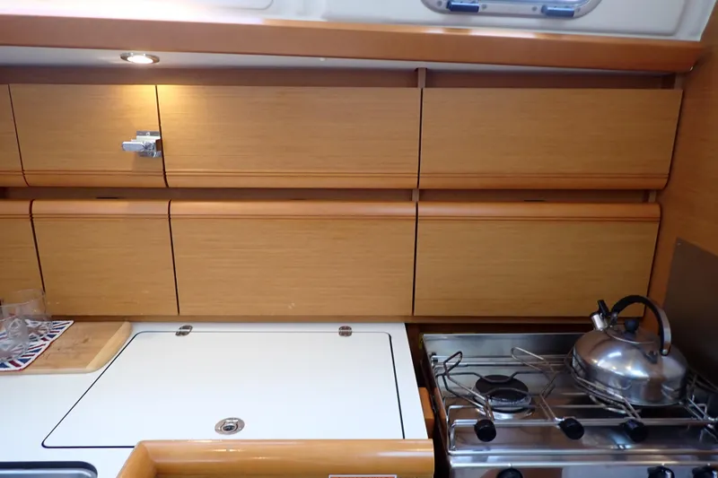 Slide: The Image of 2018 Jeanneau Sun Odyssey 389 yacht kitchen with wooden cabinets and stainless steel stove. - 103