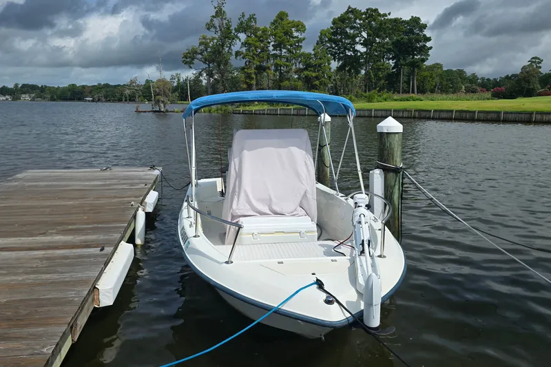 Slide: The Image of 2004 Sea Boss 180 Center Console boat docked on a calm lake under cloudy skies. - 32