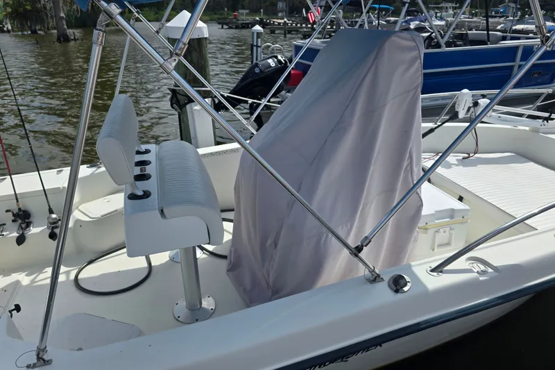 Slide: The Image of 2004 Sea Boss 180 Center Console boat docked, covered console, white seating, and fishing rods. - 29