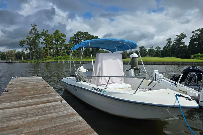 Slide: The Image of 2004 Sea Boss 180 Center Console boat docked on a calm lake under cloudy skies. - 31