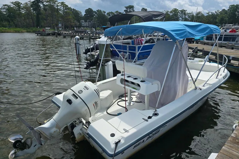 Slide: The Image of 2004 Sea Boss 180 Center Console boat docked with blue canopy and outboard motor. - 3
