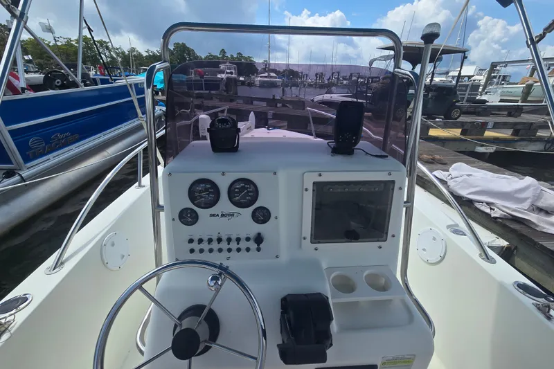 Slide: The Image of 2004 Sea Boss 180 Center Console boat dashboard with steering wheel and gauges at marina. - 25