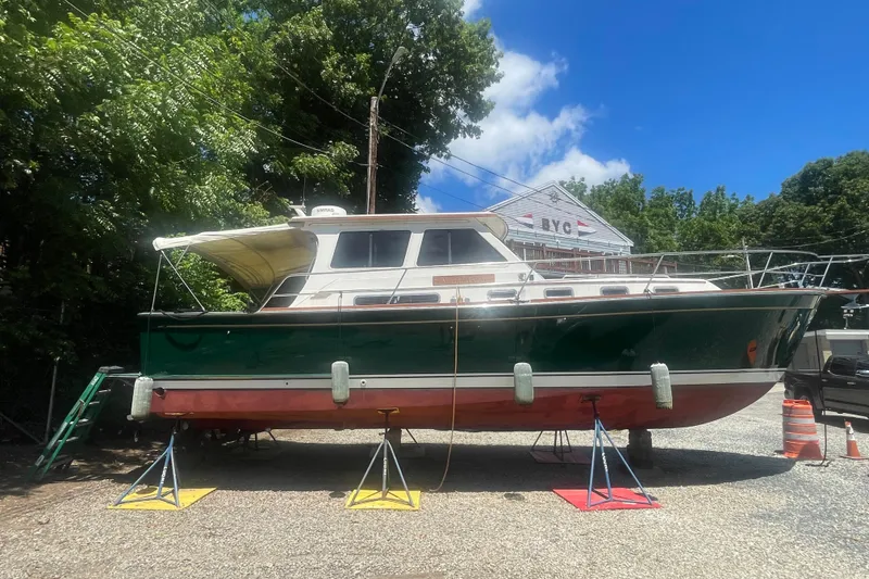 The Image of 2001 Sabre 36 Express boat on stands, surrounded by trees and a building. - 1