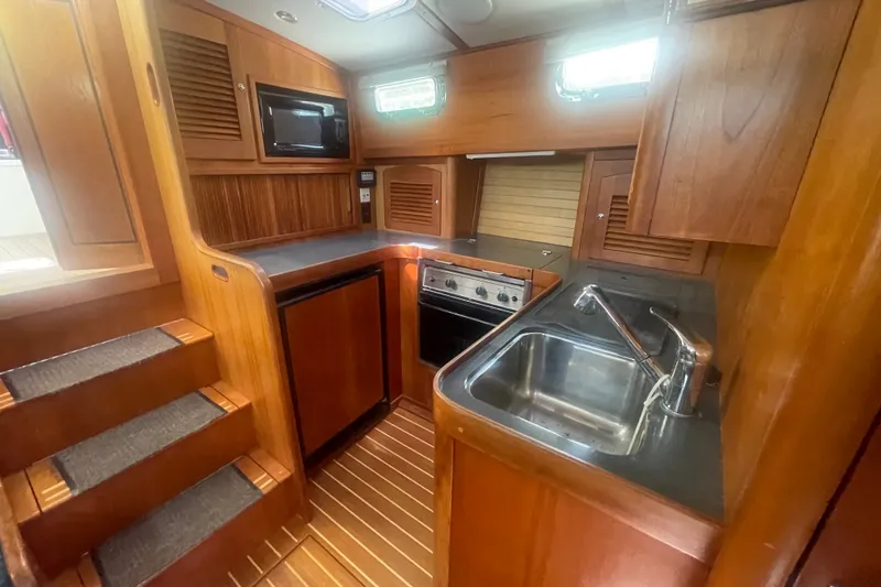 Slide: The Image of 2001 Sabre 36 Express yacht interior kitchen with wood cabinetry, sink, stove, and microwave. - 17