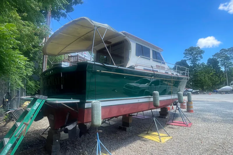 Slide: The Image of 2001 Sabre 36 Express boat on stands, green hull, canopy, outdoor setting. - 2