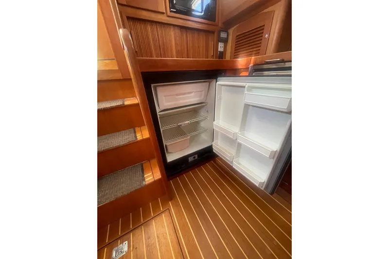 Slide: The Image of Interior of 2001 Sabre 36 Express yacht showing open refrigerator and wooden flooring. - 18