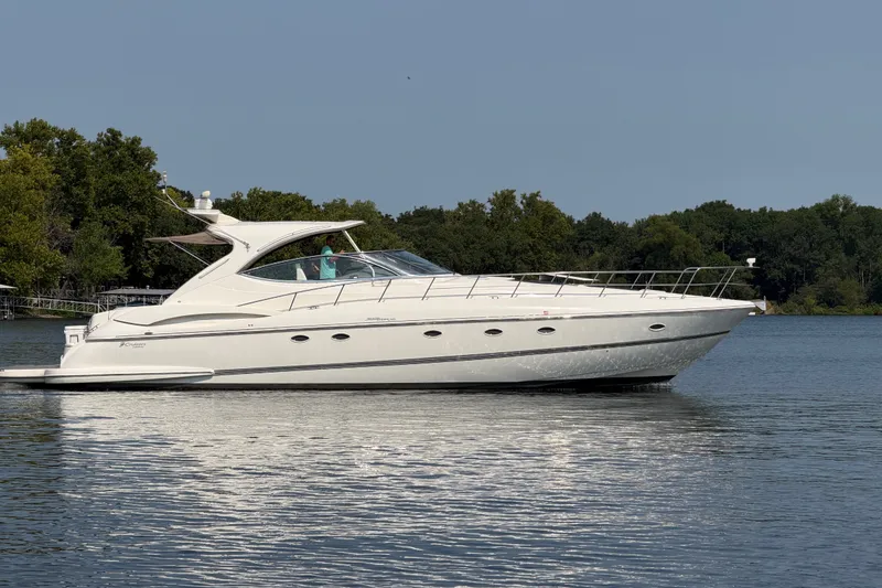 The Image of 2006 Cruisers Yachts 560 Express on a serene lake with lush green trees. - 0