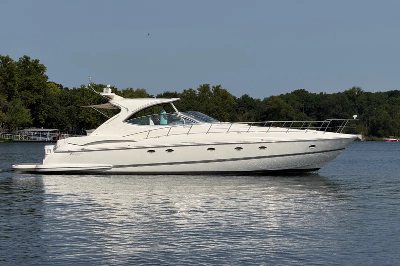 Slide: The Image of 2006 Cruisers Yachts 560 Express on a serene lake with lush green backdrop. - 1