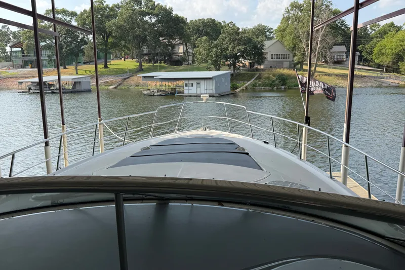 Slide: The Image of 2006 Cruisers Yachts 560 Express docked on a serene lake with lush surroundings. - 6