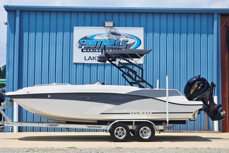 The Image of 2024 Starcraft SVX 231 OB boat on trailer at Foothills Marine, blue building background. - 1