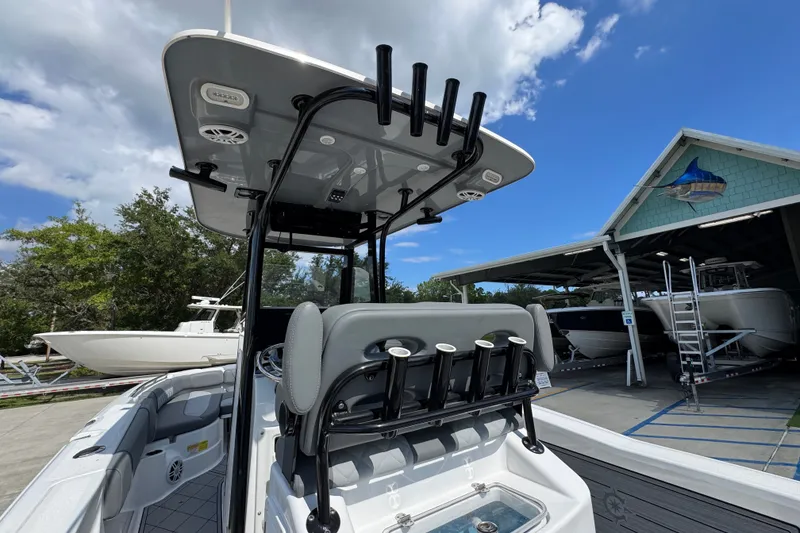 Slide: The Image of 2025 NauticStar 251 Hybrid boat with T-top and rod holders, docked under blue sky. - 39