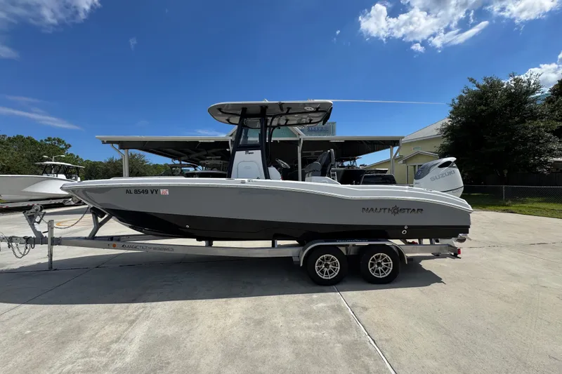 The Image of 2025 NauticStar 251 Hybrid boat on trailer under clear blue sky. - 1