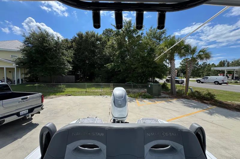 Slide: The Image of 2025 NauticStar 251 Hybrid boat parked, rear view with trees and vehicles in the background. - 31