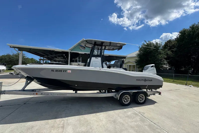 Slide: The Image of 2025 NauticStar 251 Hybrid boat on trailer under clear sky. - 2