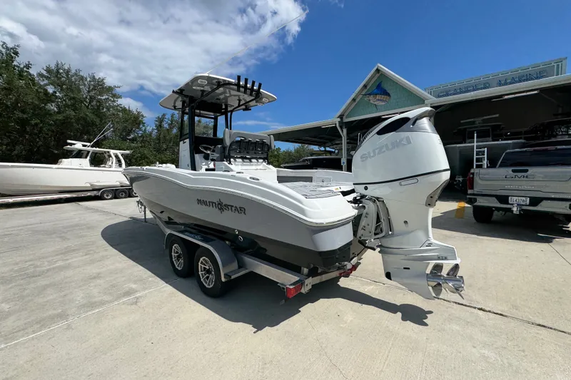 Slide: The Image of 2025 NauticStar 251 Hybrid boat with Suzuki engine on trailer, parked outdoors. - 17