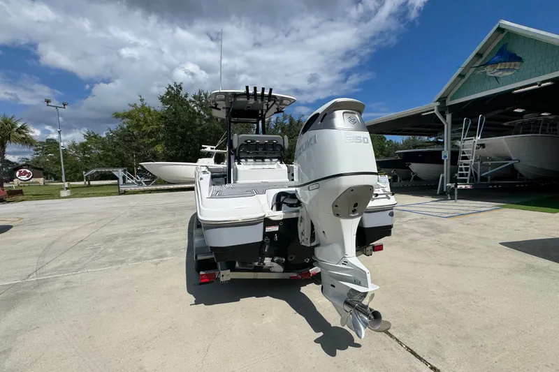 Slide: The Image of 2025 NauticStar 251 Hybrid boat with Suzuki engine, parked outdoors under a blue sky. - 16