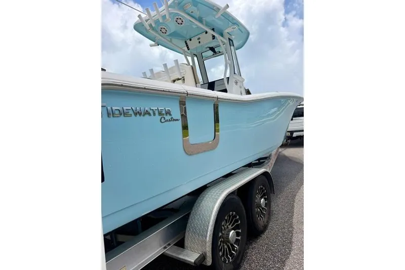 Slide: The Image of 2022 Tidewater 272 CC Adventure boat on trailer, light blue hull, clear sky background. - 4