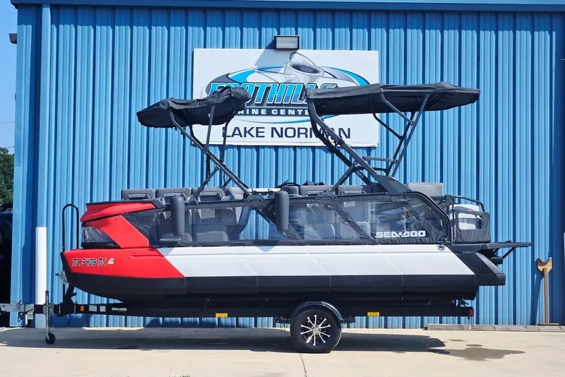 The Image of 2023 Sea-Doo Switch Cruise 21 pontoon boat on trailer, parked outside a marine center. - 1