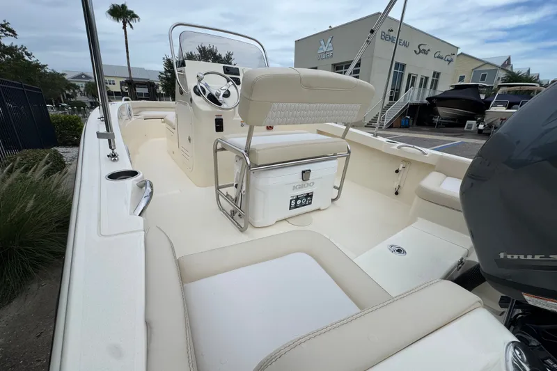 Slide: The Image of 2027 Scout 188 Sportfish boat interior with steering console and seating in a marina setting. - 10