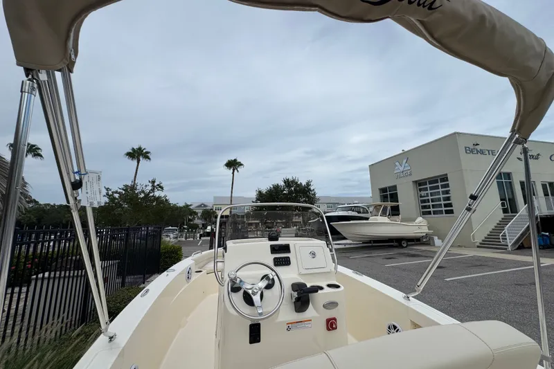 Slide: The Image of 2027 Scout 188 Sportfish boat with steering wheel, parked near dealership under cloudy sky. - 9