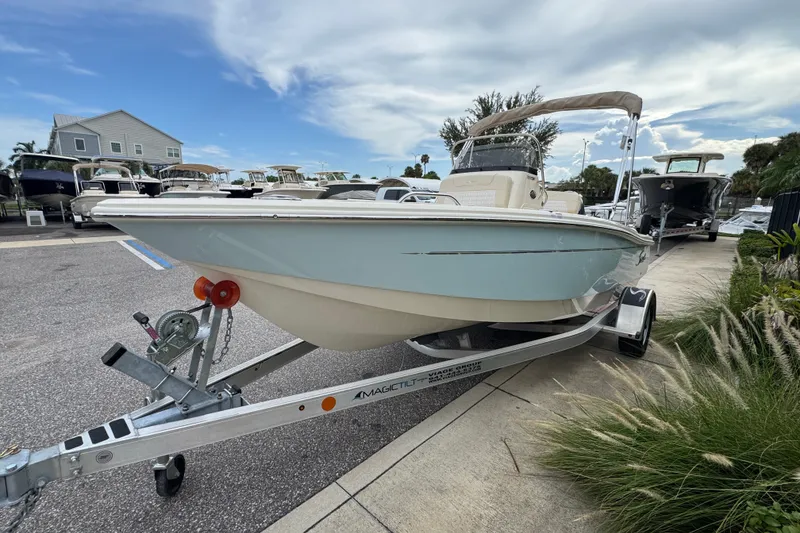 Slide: The Image of 2027 Scout 188 Sportfish boat on trailer, parked outdoors under a cloudy sky. - 2