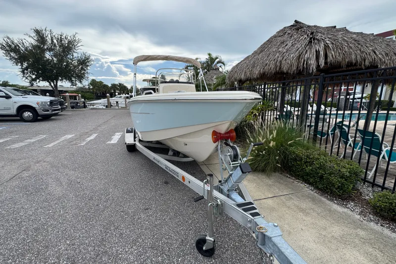 Slide: The Image of 2027 Scout 188 Sportfish boat on trailer, parked near tropical-themed area. - 4